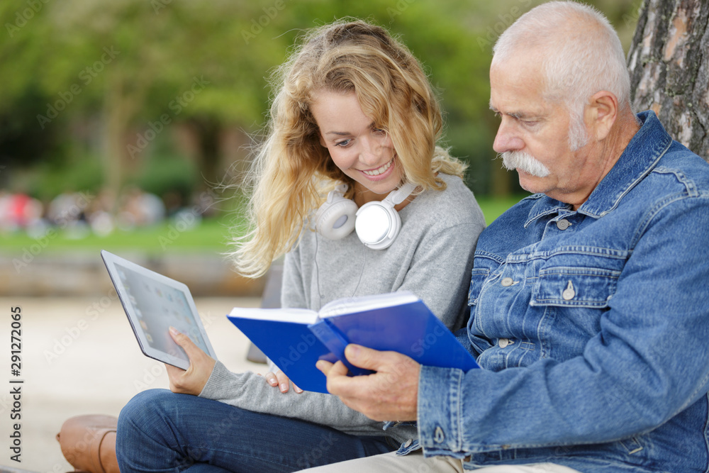 senior man and woman reading a book in park senior man and woman reading a book in park