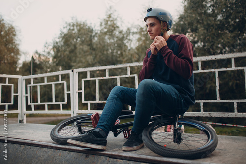 Professional young sports man cyclist with bmx bike at skatepark