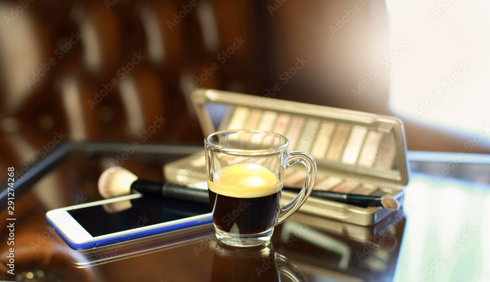 Cup of coffee with the phone and make-up set, shadow palette, and brushes Cup of coffee with the phone and make-up set, shadow palette, and brushes