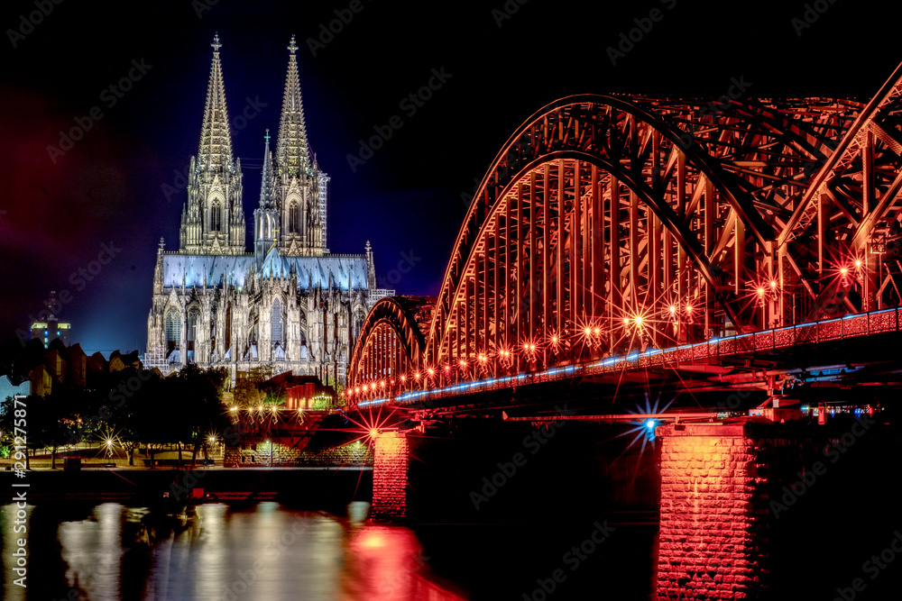 Fototapeta premium Night View of Cologne Cathedral (Kolner Dom) and Rhine river under the Hohenzollern Bridge, Cologne city skyline at night, North Rhine Westphalia region, Germany.