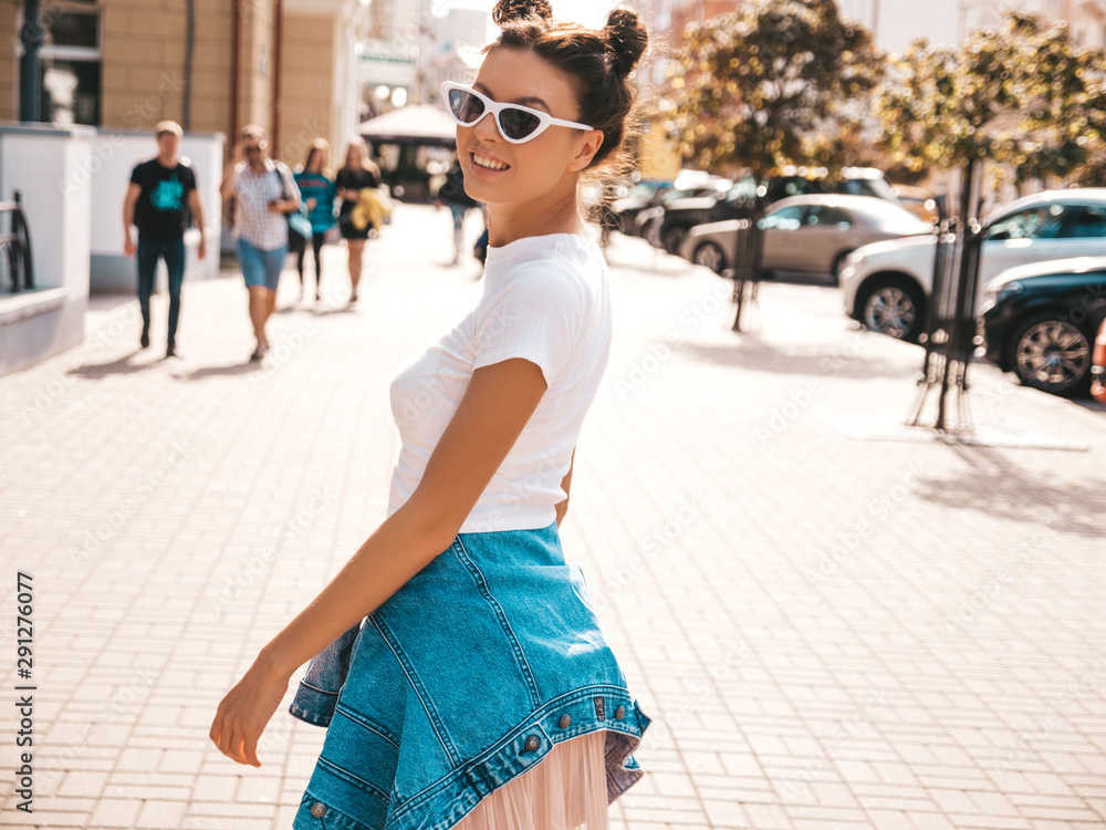 Beautiful smiling model with horns hairstyle dressed in summer hipster jacket jeans clothes.Sexy carefree girl posing in the street background.Trendy funny and positive woman having fun in sunglasses