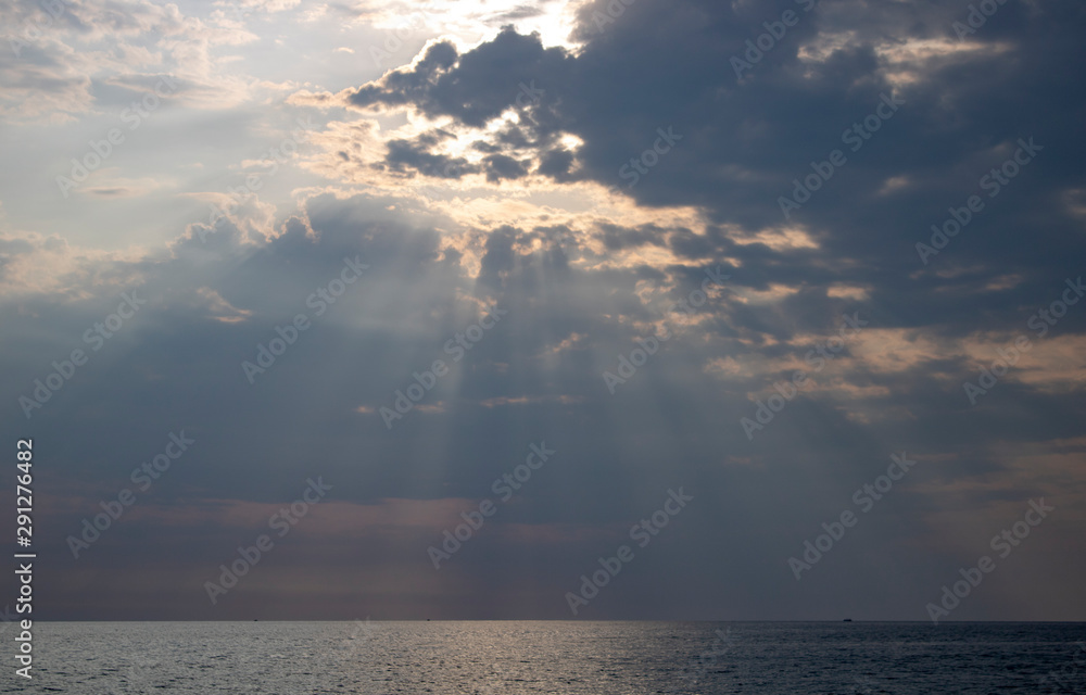 Summer rays of the sun pierce the clouds over the Black Sea