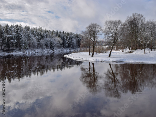 view of beautiful river winter day, snowy trees, many clouds, beautiful reflections, calm river water, Gauja river, Valmiera, Latvia