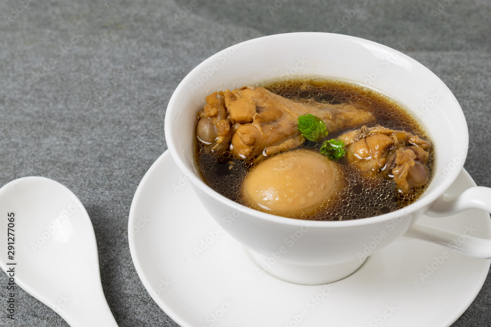Hard-boiled eggs and chicken in sweet gravy soup in white bowl on tile table. Hard-boiled eggs and chicken in sweet gravy soup in white bowl on tile table.