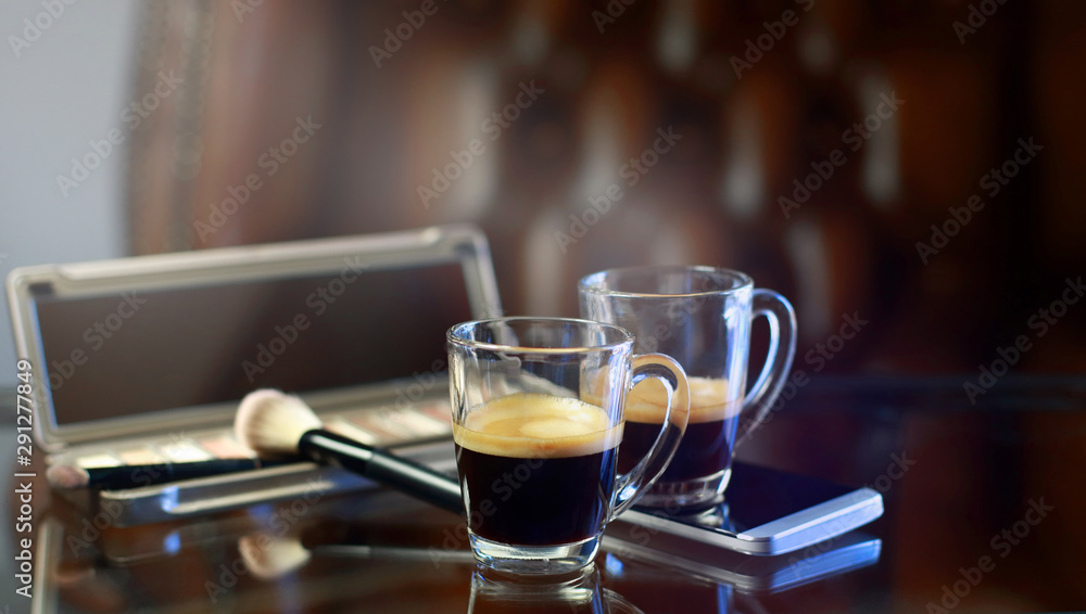 Cup of coffee with the phone and make-up set, shadow palette, and brushes Cup of coffee with the phone and make-up set, shadow palette, and brushes
