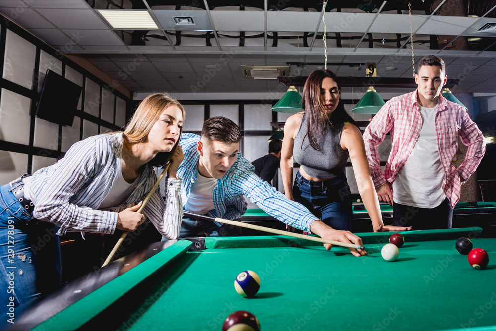 Fototapeta premium Group of young cheerful friends playing billiards.