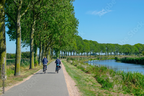 Two unrecognizable cyclists cycle in polder