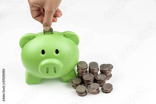 Hand insert coin into the green piggy bank, isolated on white photo