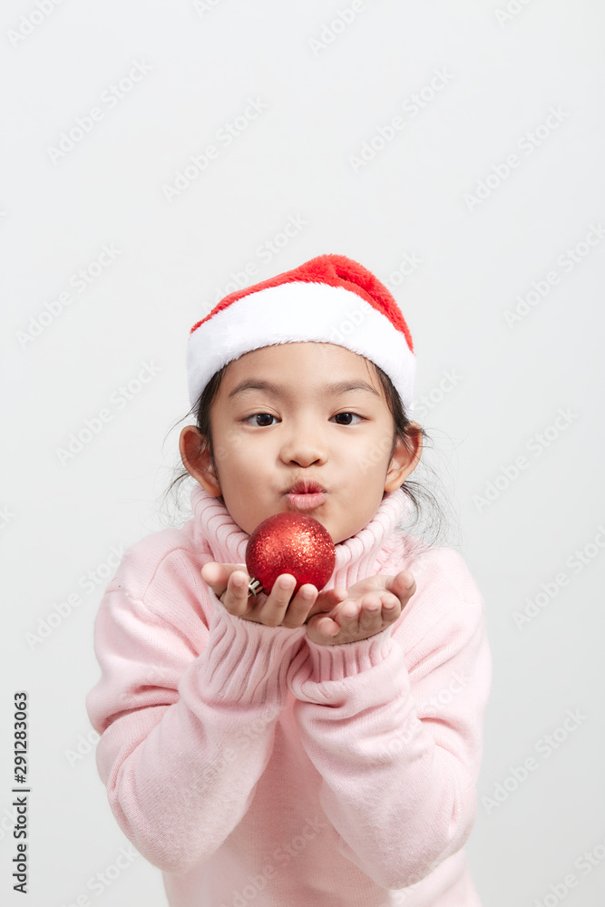 Girl holding a red christmas ball in sweater and santa hat Girl holding a red christmas ball in sweater and santa hat
