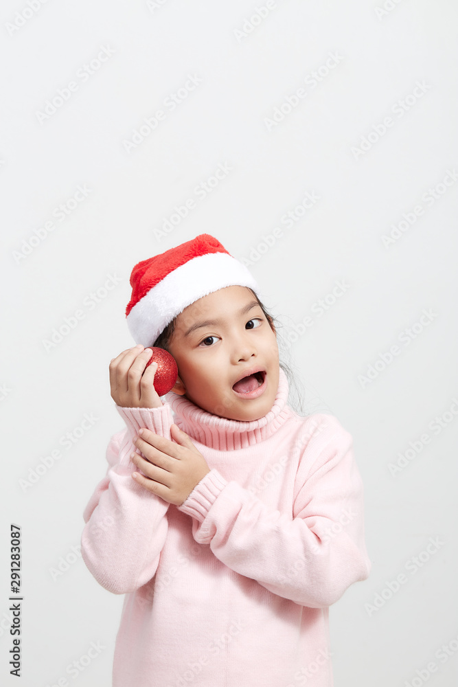 Girl holding a red christmas ball in sweater and santa hat Girl holding a red christmas ball in sweater and santa hat