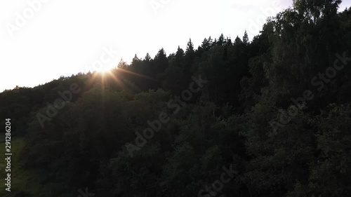 Aerial view of the dark evening forest and sunset with sunbeams.
