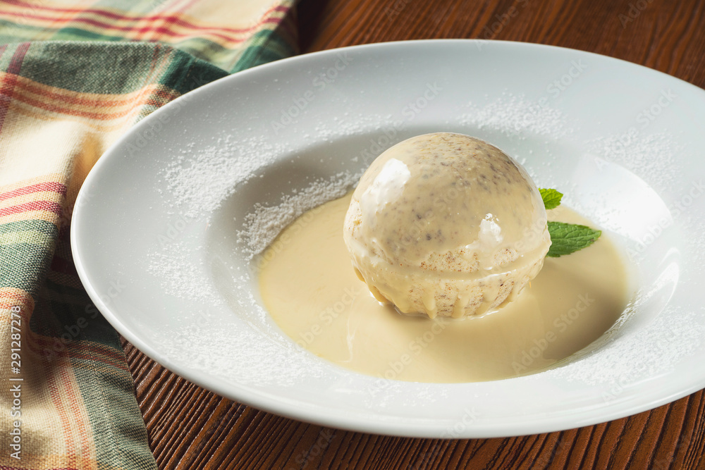 Close up White italian ice-cream into white chocolate ball with melted white chocolate in plate with mint. Italian dessert. Selective focus Close up White italian ice-cream into white chocolate ball with melted white chocolate in plate with mint. Italian dessert. Selective focus