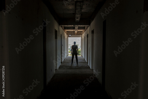 A person standing in dark corridor of abandoned building