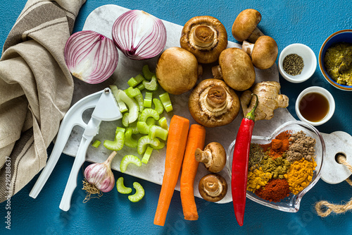 Ingredients for cooking Indian curry from vegetables, pumpkins and mushrooms on a blue background and spices. shot from above. copy space