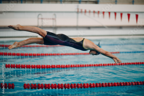 Young woman swimmer jumping in swimming pool