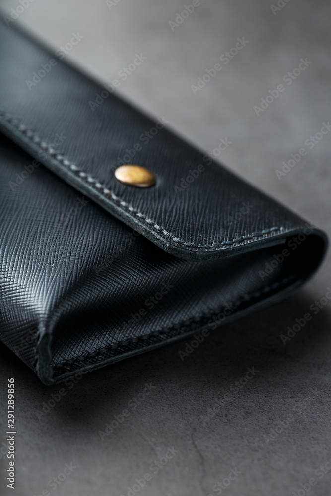 Black wallet made of genuine leather on a dark background. Handmade leather items Black wallet made of genuine leather on a dark background. Handmade leather items
