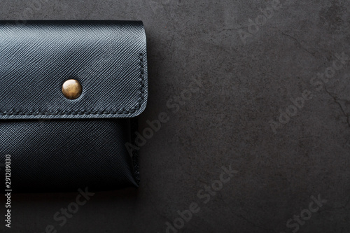 Black wallet made of genuine leather on a dark background. Handmade leather items