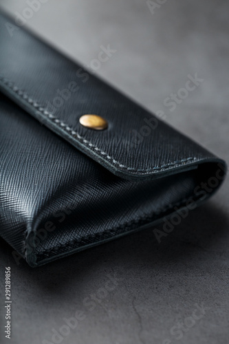 Black wallet made of genuine leather on a dark background. Handmade leather items