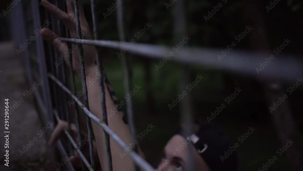 guy and girl touch each other with their fingers through an iron cage. guy and girl touch each other with their fingers through an iron cage.