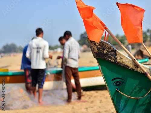 Photography The fishermen are fixing nets to beside the traditional fishing boat on the beach, Gokarna, India