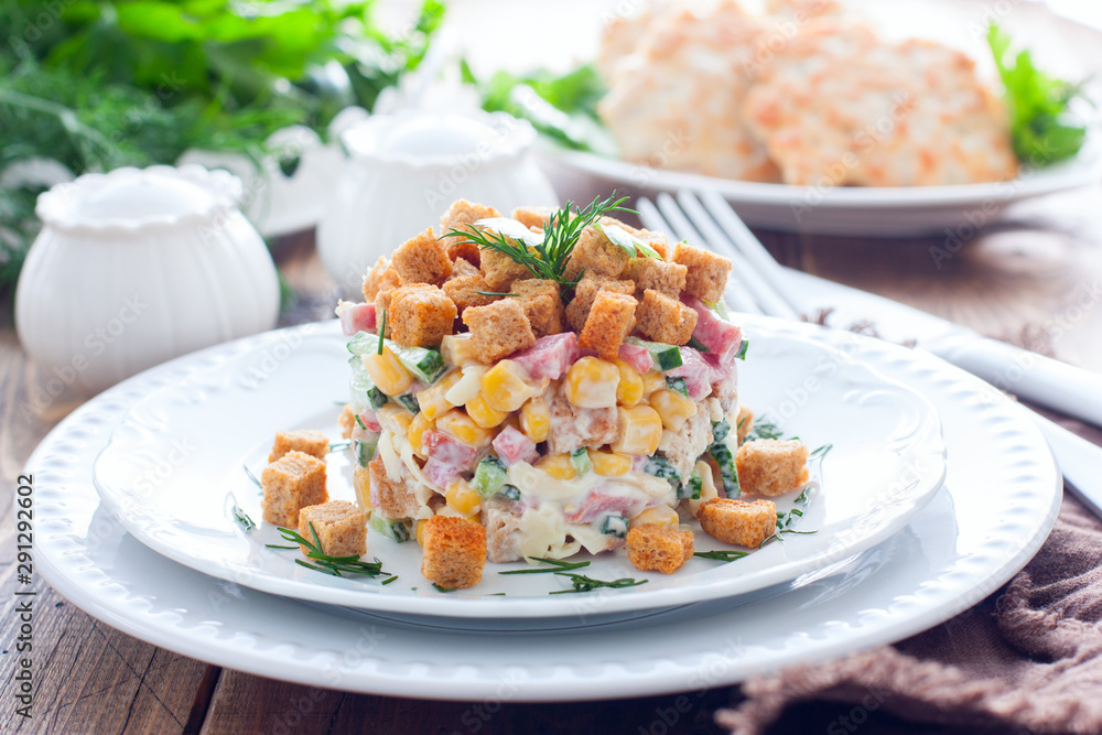 Salad with smoked sausage and crackers on a white plate in a portion serving, horizontal Salad with smoked sausage and crackers on a white plate in a portion serving, horizontal