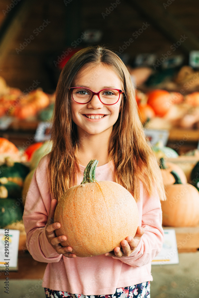 Fototapeta premium Adorable little girl choosing halloween pumpkin on farm market
