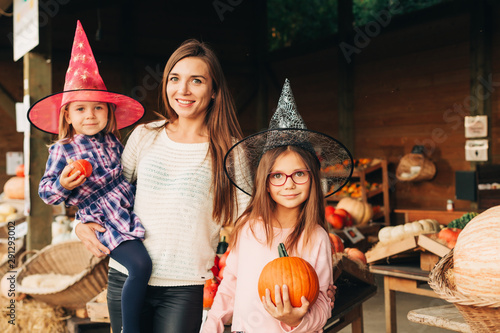 Family with kids choosing halloween pumpkin on farm market