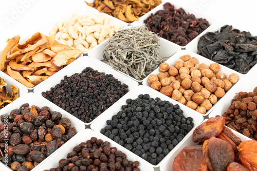 Groups of various kinds of dried fruits in square white bowls on white background