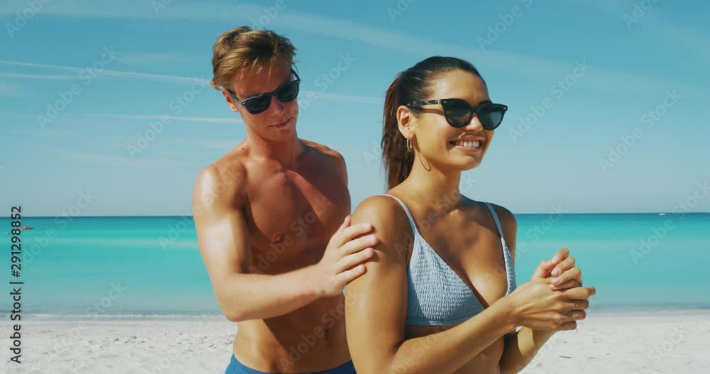 Slow motion of happy young couple is having fun to apply a sunscreen or sun tanning lotion to take care of their skin during a vacation on a beach. Slow motion of happy young couple is having fun to apply a sunscreen or sun tanning lotion to take care of their skin during a vacation on a beach.