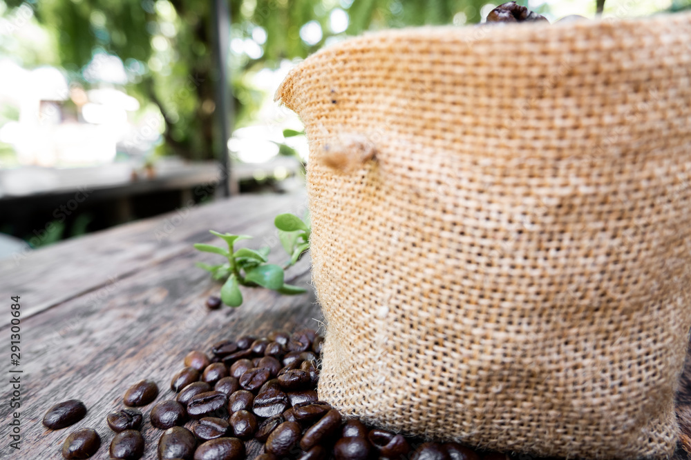 full of coffee beans spilling out bag on brown wooden background