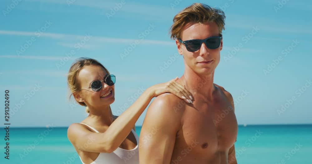 Slow motion of happy young couple is having fun to apply a sunscreen or sun tanning lotion to take care of their skin during a vacation on a beach. Slow motion of happy young couple is having fun to apply a sunscreen or sun tanning lotion to take care of their skin during a vacation on a beach.