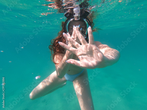 Young student female swimming underwater  waving and having fun in summer