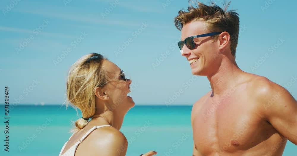 Slow motion of happy young couple is having fun to apply a sunscreen or sun tanning lotion to take care of their skin during a vacation on a beach. Slow motion of happy young couple is having fun to apply a sunscreen or sun tanning lotion to take care of their skin during a vacation on a beach.