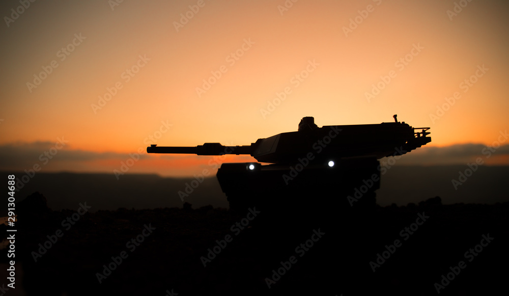 Fototapeta premium War Concept. Armored vehicle silhouette fighting scene on war fog sky background. American tank at sunset.