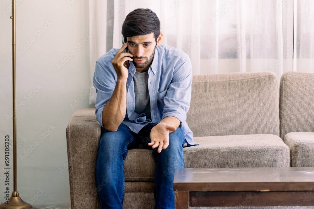 Obraz premium Caucasian man with mustache and beard talking with mobile phone in living room about serious problem