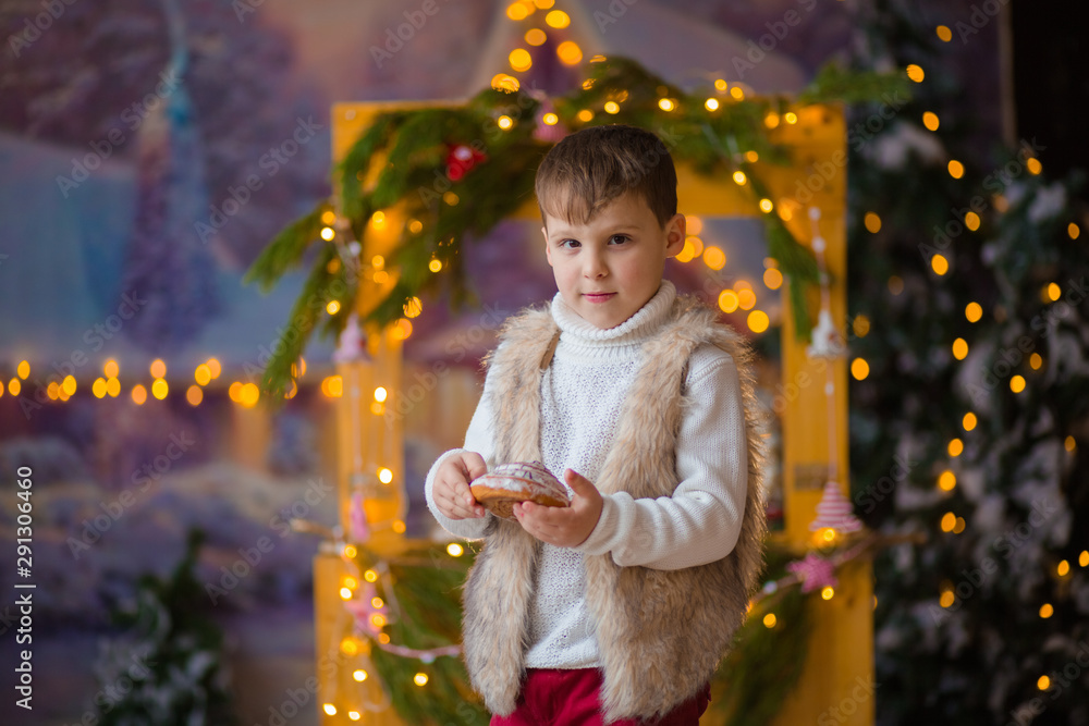 little cute boy with cookies in hands on the background of the Christmas counter in anticipation of the holiday