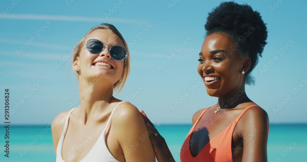 Slow motion of happy young different ethnicity girlfriends are having fun to apply a sunscreen or sun tanning lotion to take care of their skin during a vacation on a beach. Slow motion of happy young different ethnicity girlfriends are having fun to apply a sunscreen or sun tanning lotion to take care of their skin during a vacation on a beach.