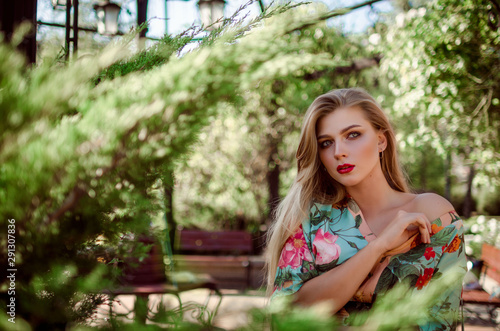 A young girl of European race with very long, blond hair in a beautiful summer dress. Girl walking in a beautiful summer park. Bright and bright summer photo.