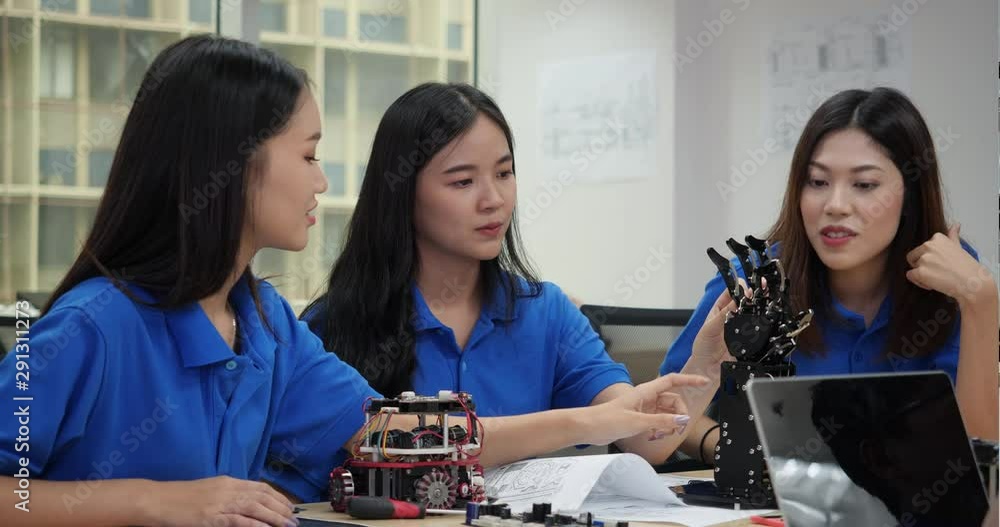 Asian engineer team assembling and testing robotics responses in ...