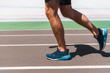 partial view of athletic young sportsman in sneakers jogging on running track in sunshine
