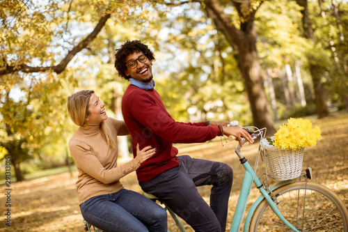 Multiracial couple riding on a bicycle at the autumn park