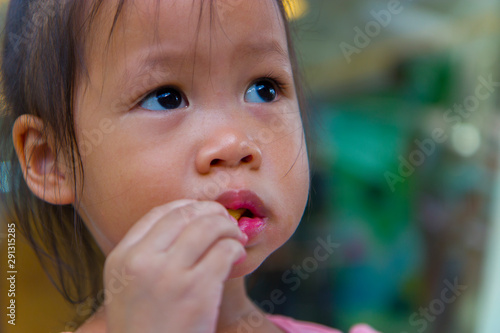 Adorable asian child smiling and enjoy eating breaded sticks at restaurant in her lunch. photo