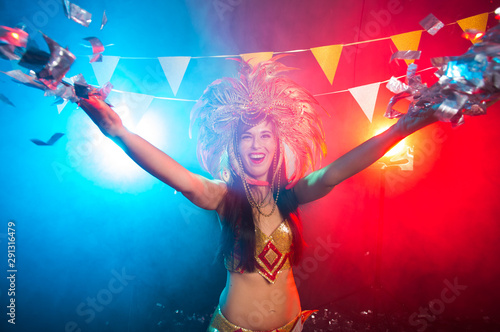 Cabaret, dancer and holidays concept - Cute young girl in bright colorful carnival costume on dark background