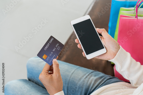 Asian woman online shopping with credit card and tablet sitting on sofa at home, digital lifestyle with technology, e-commerce concept