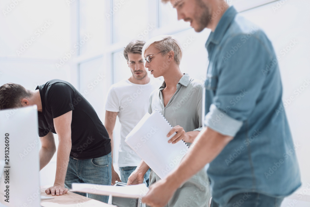 group of designers with sketches standing near the desktop group of designers with sketches standing near the desktop
