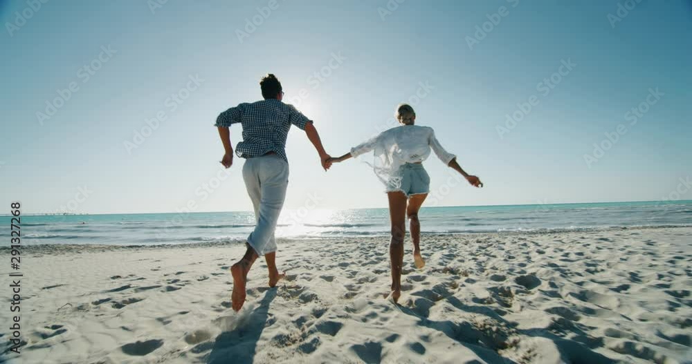 Slow motion of young carefree couple is having fun and enjoying their summer vacation together on a beach with a sea in a sunny day.