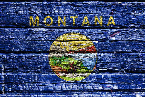 The national flag of the US state Montana in against a black charred wooden wall on the day of independence. Political and religious disputes  fire department and firefighters.