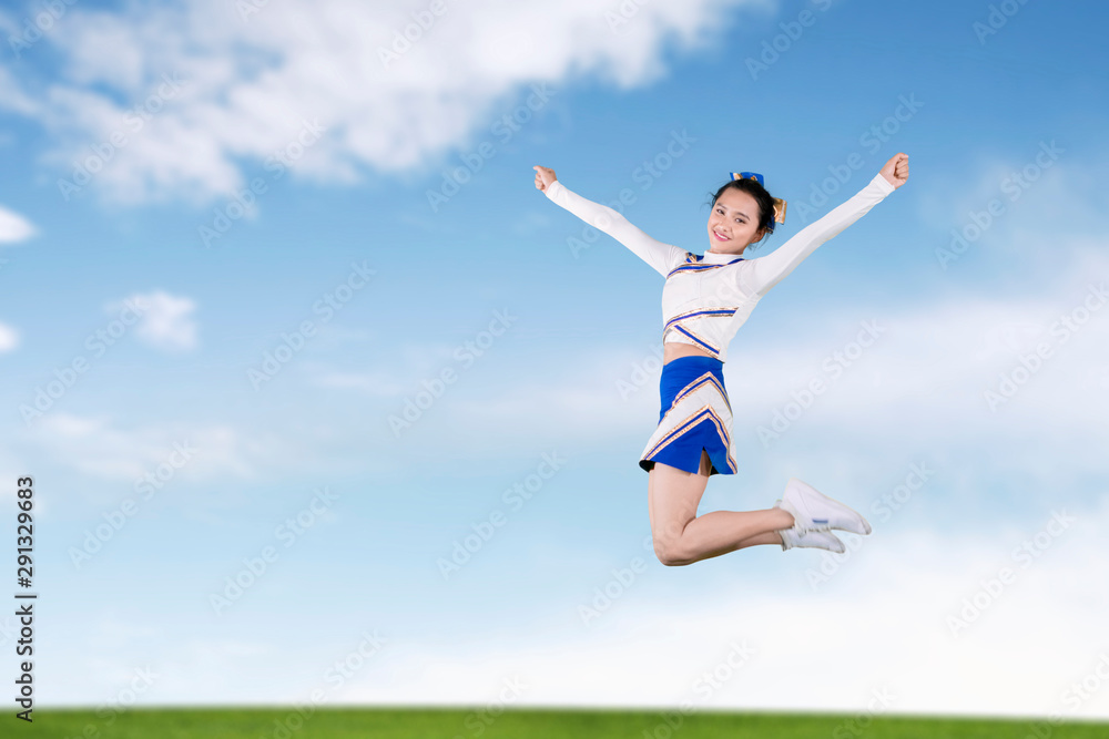 Beautiful cheerleader leaping in the meadow Beautiful cheerleader leaping in the meadow