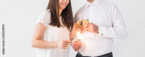 New year, holidays, date and valentines day concept - Loving couple holding sparklers light and glasses of champagne close-up over white background