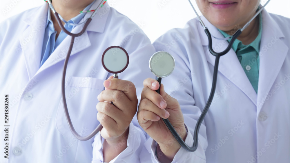 Two senior physicians stand holding medical stethoscope at the same time to serve patients in the hospital or clinic. Medical concepts out of focus on the use of medical equipment. Two senior physicians stand holding medical stethoscope at the same time to serve patients in the hospital or clinic. Medical concepts out of focus on the use of medical equipment.